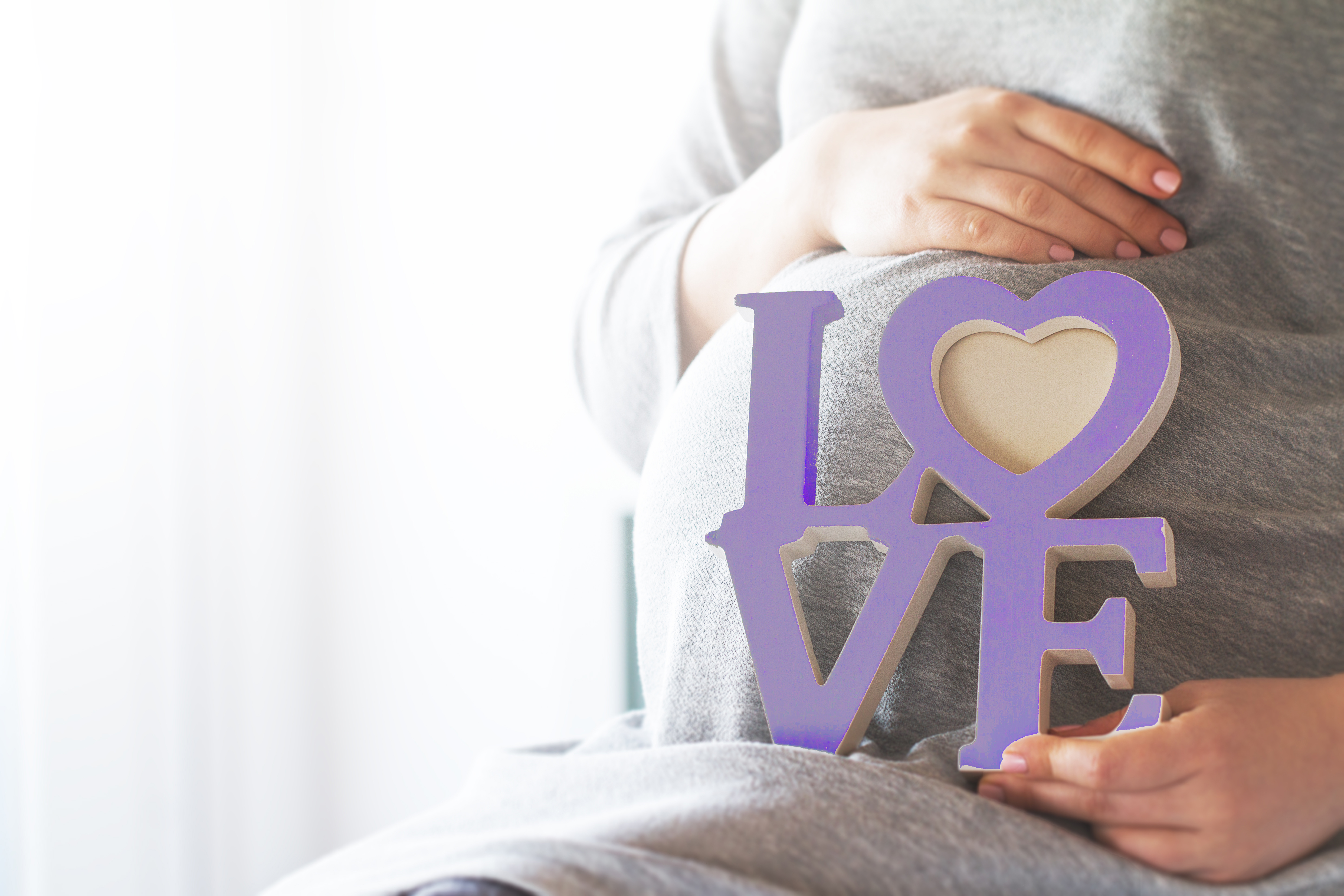 Young pregnant woman holds wooden letters LOVE. Love concept.